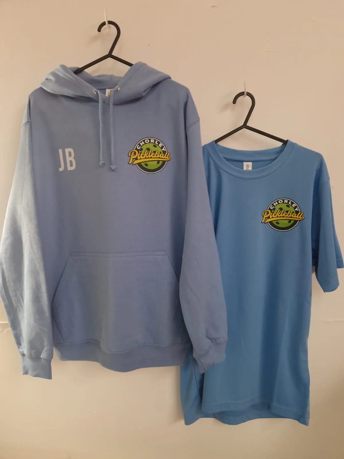 Light blue Chorley Pickleball hoodie and t-shirt with chest logos and initials