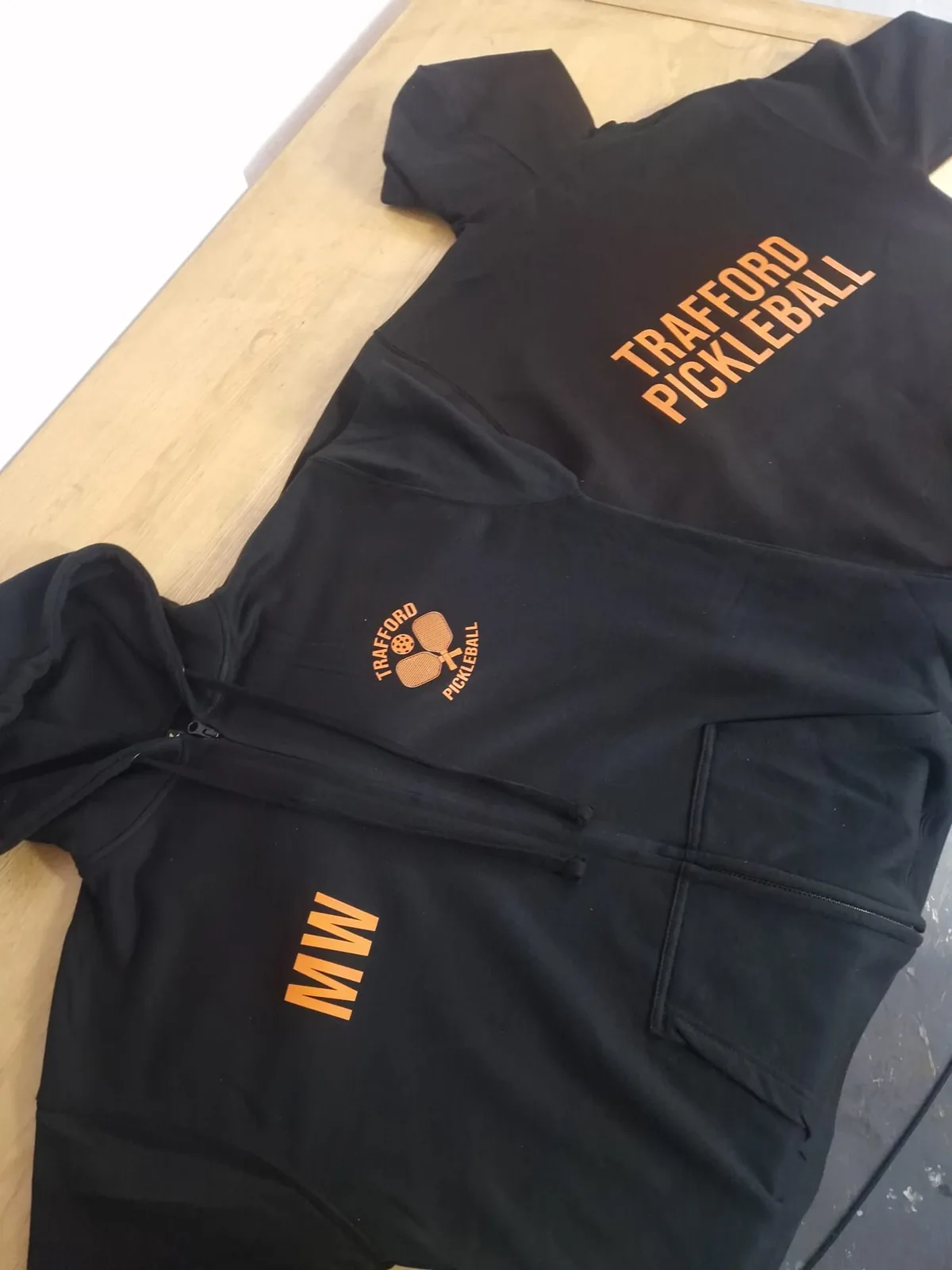 Black and orange Trafford Pickleball teamwear with club branding and initials